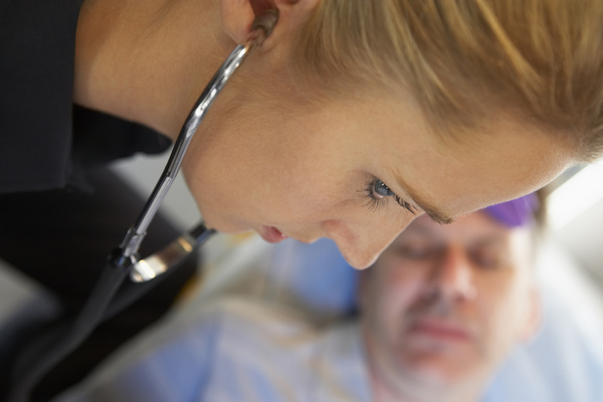 Paramedic using stethoscope on patient